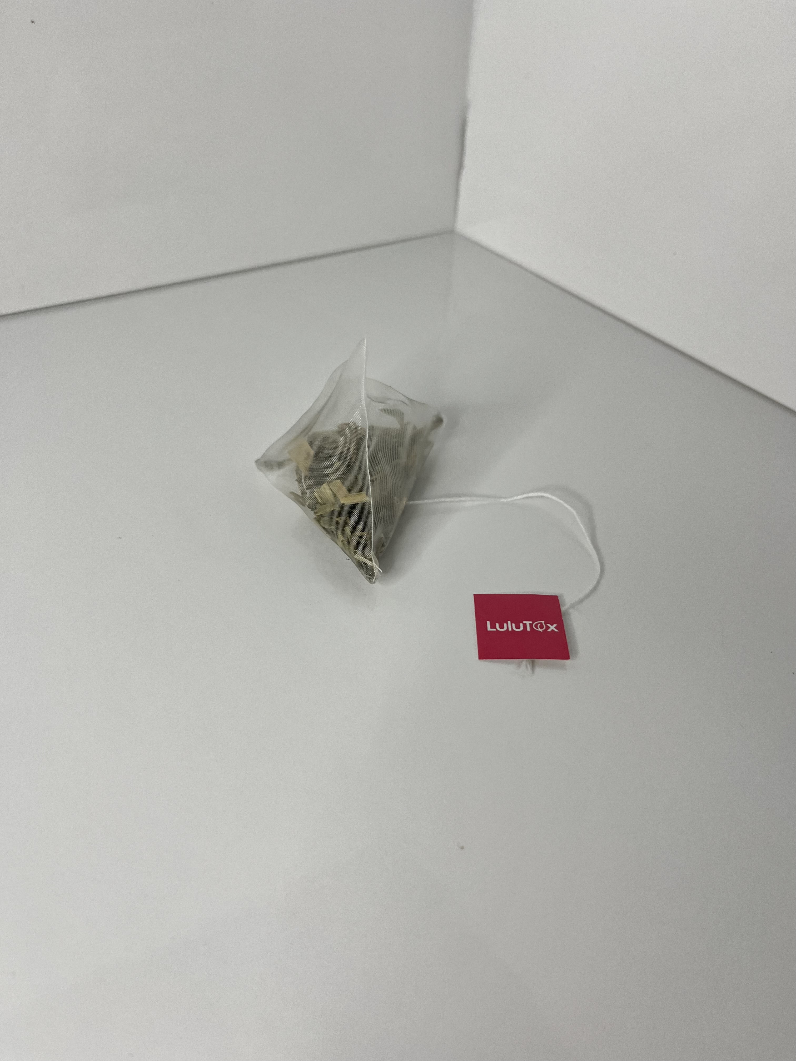 Another angled view of the tea bag shows its transparent mesh and visible dried herbs inside.