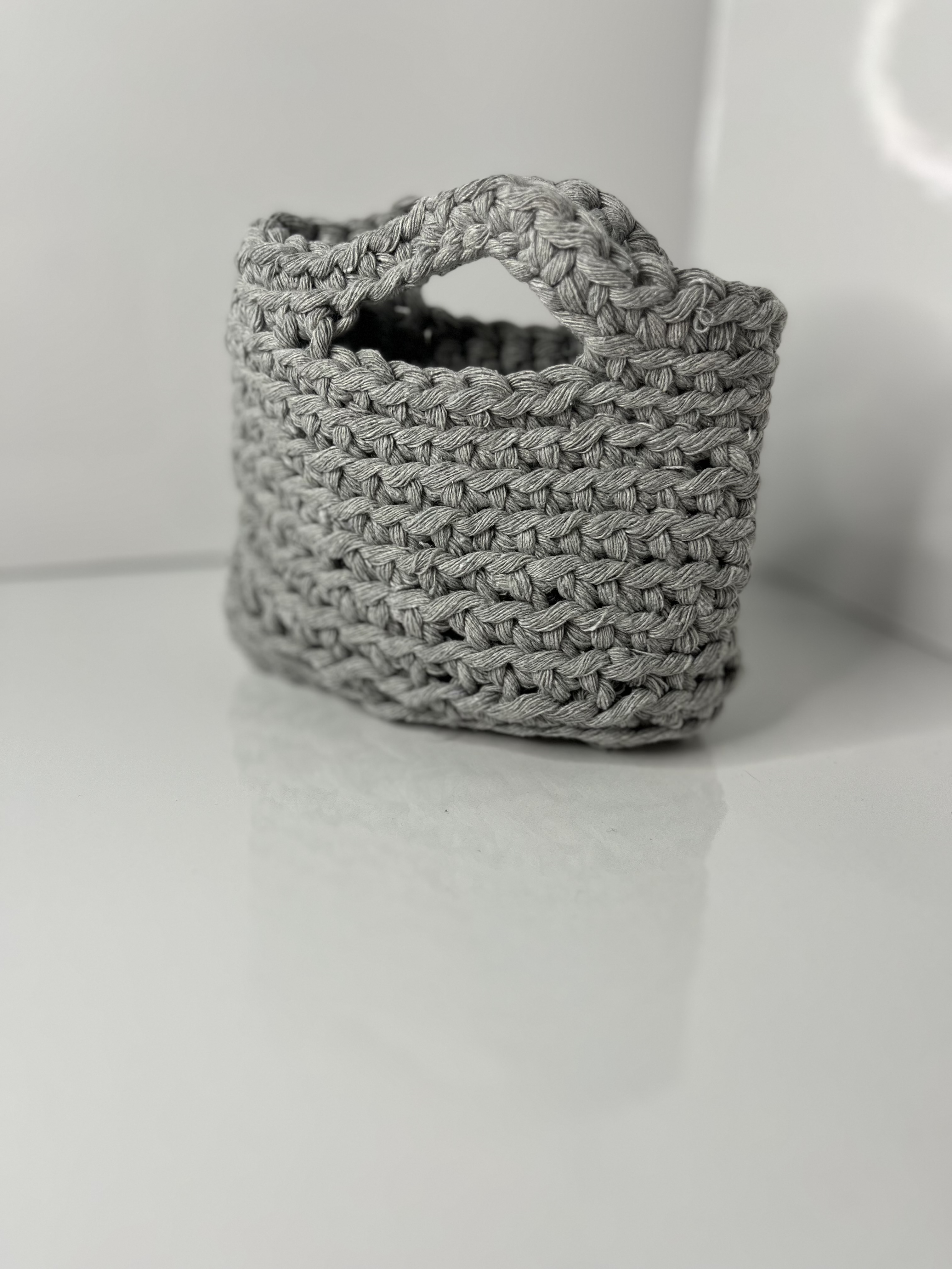 The bag is turned slightly, capturing its structural curves and shadow details on the reflective surface.