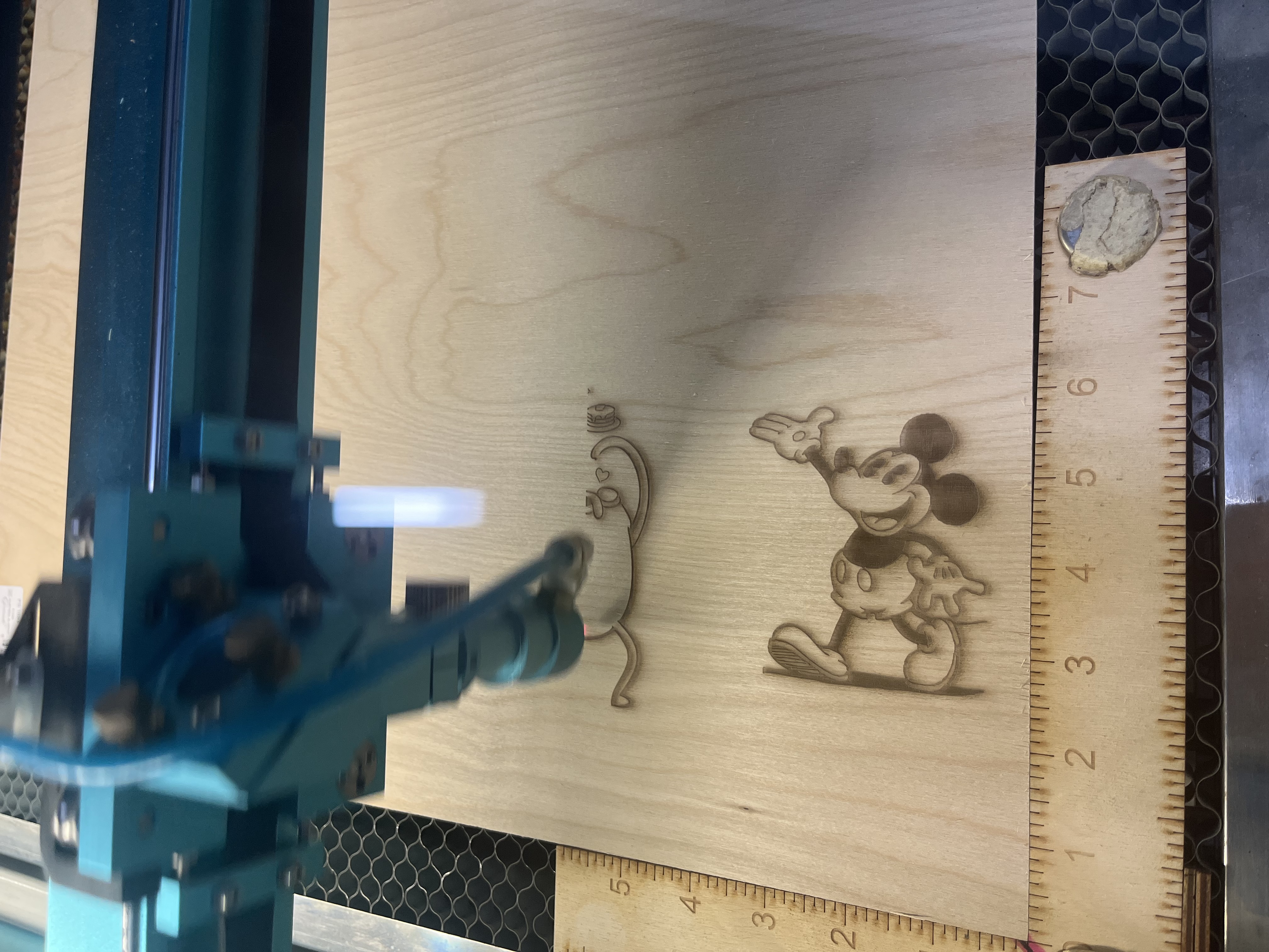 The cutting head moves across the board, deepening engravings of multiple illustrated characters arranged in a grid layout.